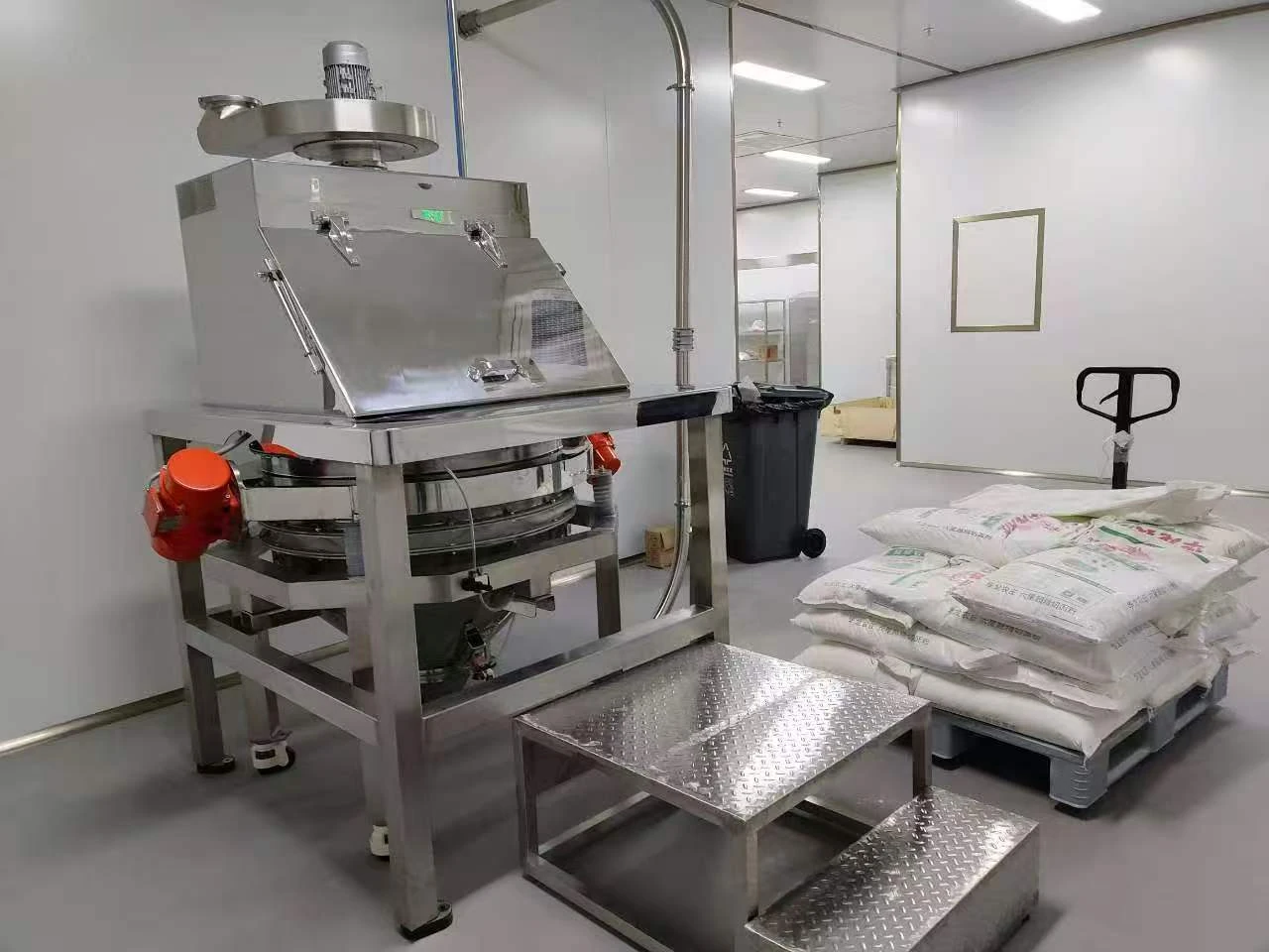 Original installed dust-controlled vibrating sifter showing loading enclosure, circular screen and lower hopper