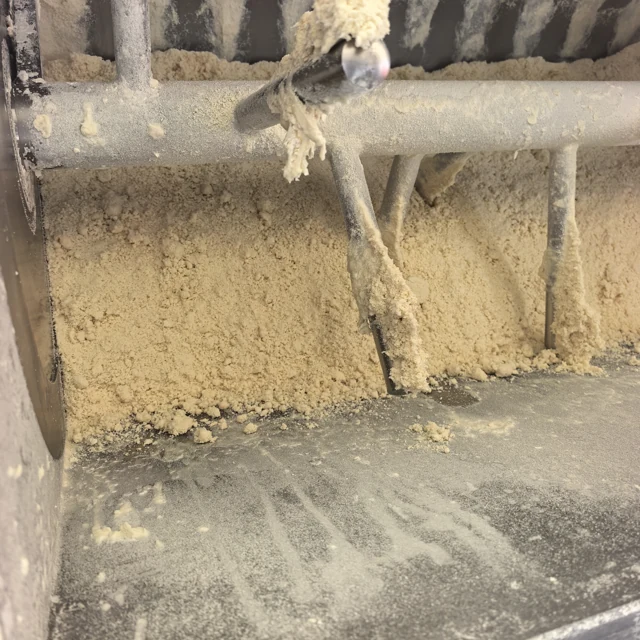 Granular dough across the mixer chamber with small clumps on the shaft and bars